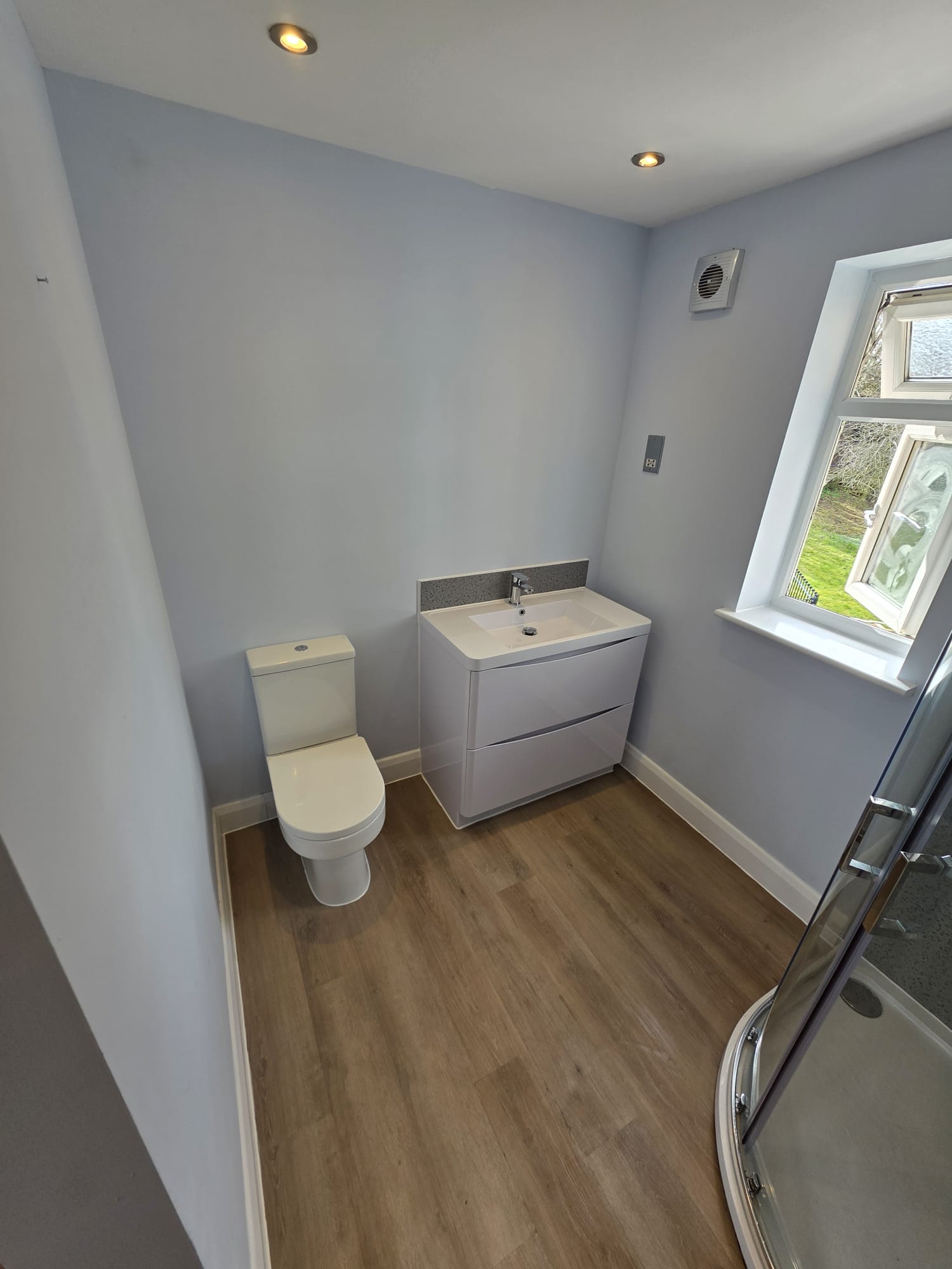 Modern cloakroom installation with vanity unit, WC and wood-effect flooring, Surrey